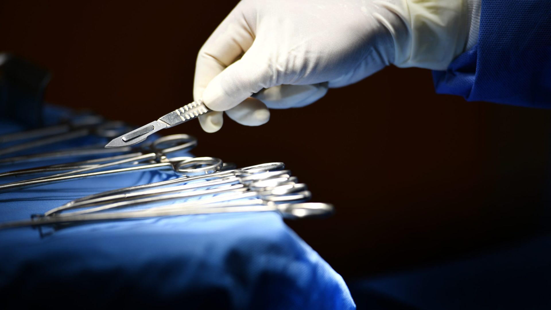 Surgeon,Hand,Picking,Up,An,Instrument,From,Tray,Of,Surgical