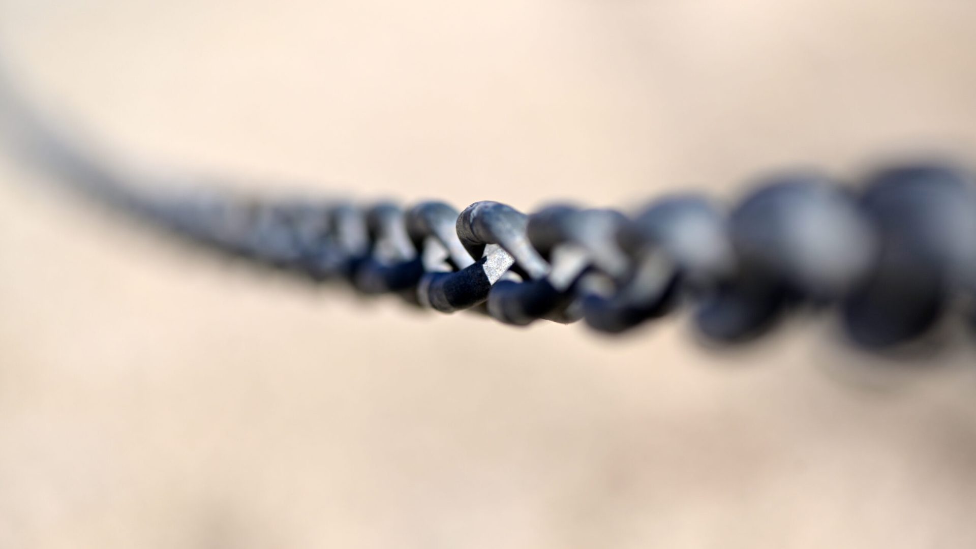 A,Diagonal,,Partial,Blurred,Iron,Chain,In,Front,Of,A